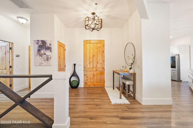 foyer entrance with an inviting chandelier and light hardwood / wood-style flooring