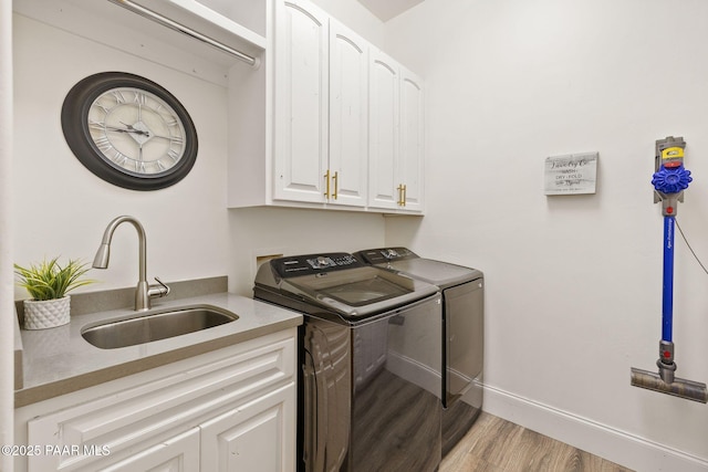 laundry room with cabinets, washing machine and dryer, sink, and light hardwood / wood-style floors