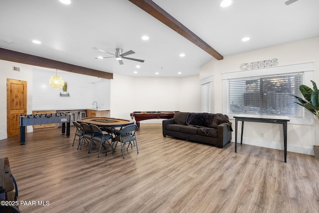 dining area featuring sink, beam ceiling, light hardwood / wood-style floors, and ceiling fan