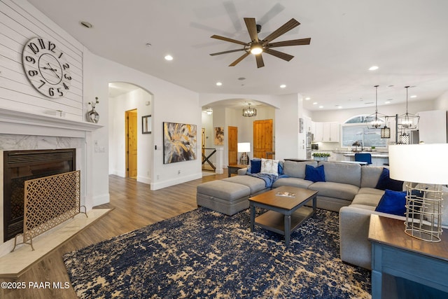 living room featuring ceiling fan with notable chandelier, sink, a fireplace, and hardwood / wood-style floors