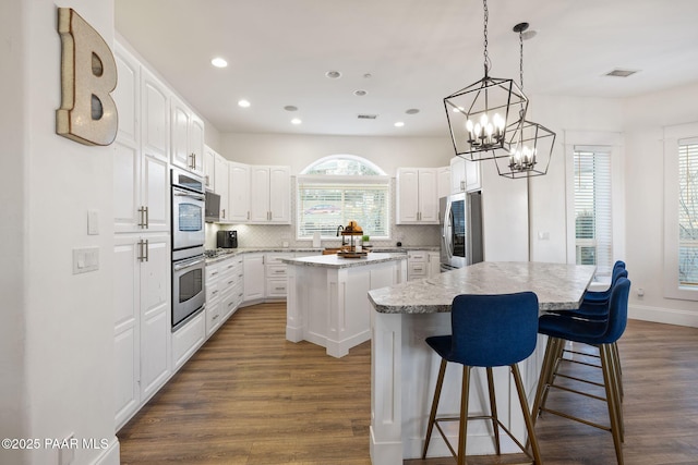 kitchen featuring white cabinetry, appliances with stainless steel finishes, a center island, and dark hardwood / wood-style flooring