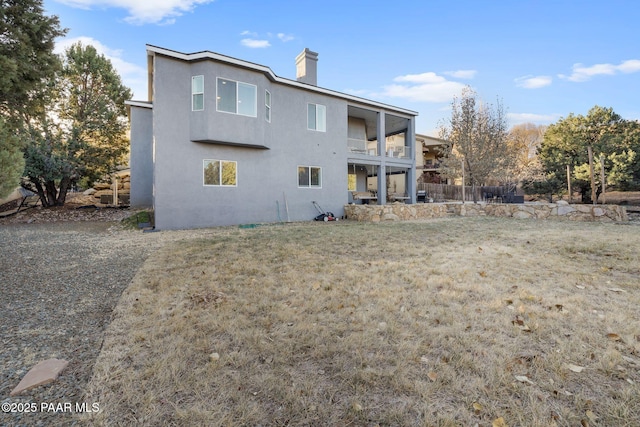 back of house featuring a balcony and a yard