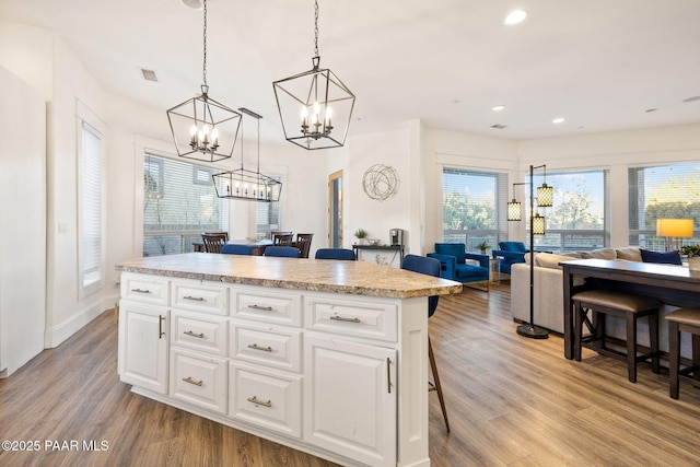 kitchen with a breakfast bar, hanging light fixtures, a kitchen island, and white cabinets