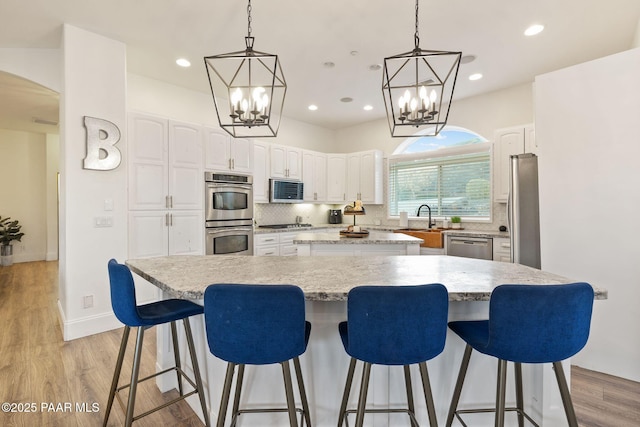 kitchen with white cabinetry, stainless steel appliances, a large island, and tasteful backsplash