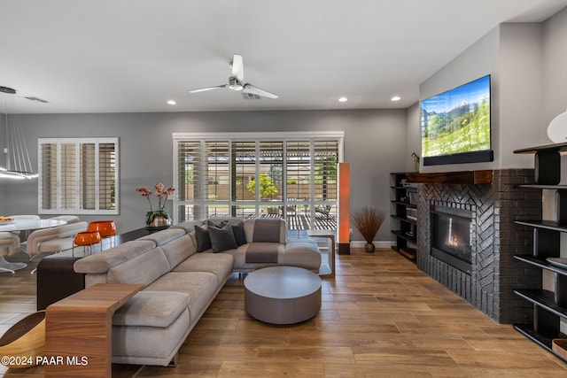 living room with recessed lighting, wood finished floors, a glass covered fireplace, and a ceiling fan