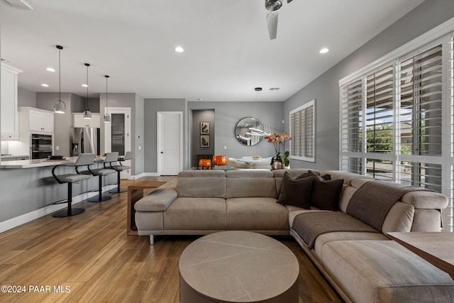living area with baseboards, light wood-style floors, recessed lighting, and a ceiling fan