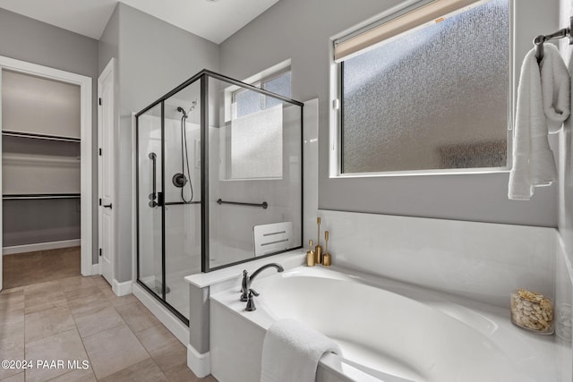 bathroom with a stall shower, a walk in closet, and a garden tub