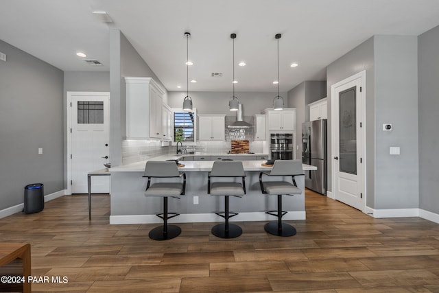 kitchen with wall chimney exhaust hood, a peninsula, a kitchen bar, and stainless steel appliances