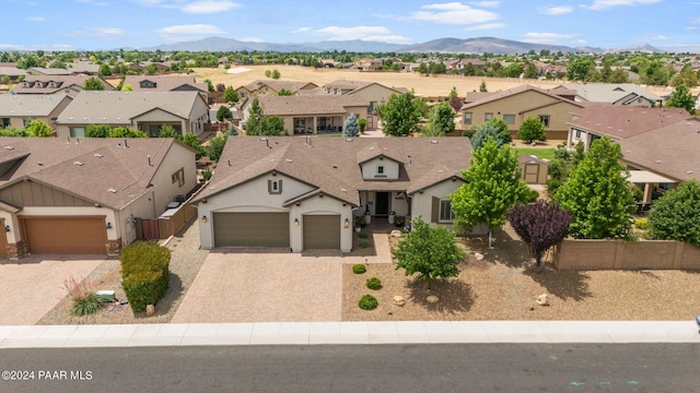 view of front of house featuring decorative driveway, an attached garage, a residential view, stucco siding, and a mountain view