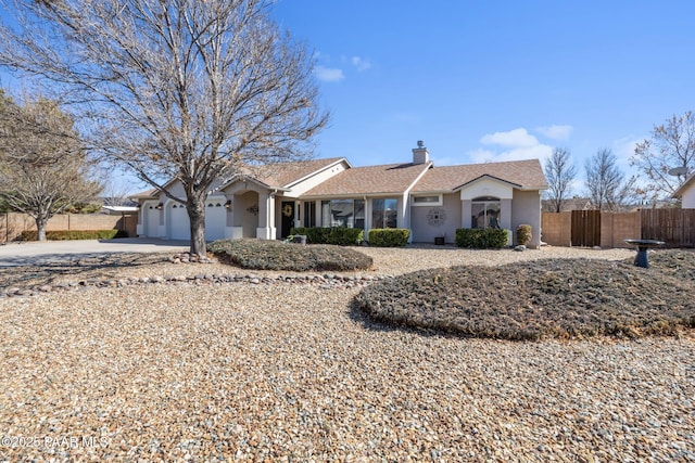 ranch-style home with a chimney, stucco siding, concrete driveway, an attached garage, and fence