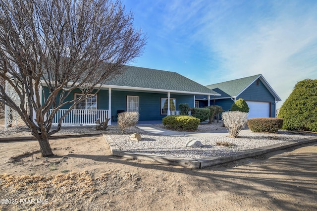 ranch-style house featuring a shingled roof, covered porch, and an attached garage