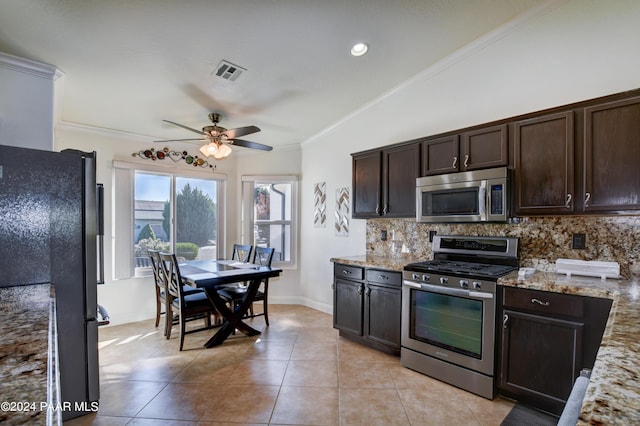 kitchen featuring light stone counters, dark brown cabinets, stainless steel appliances, and vaulted ceiling