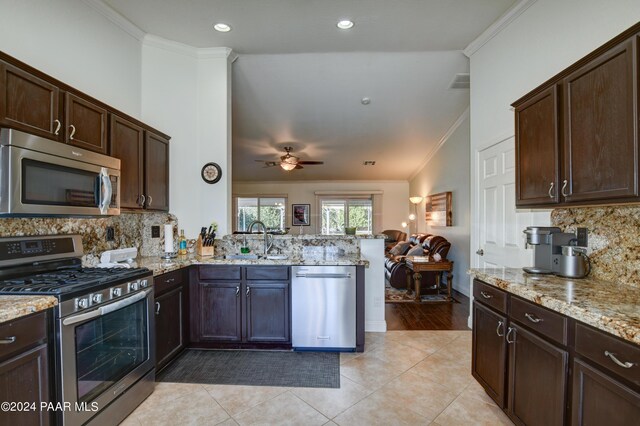 kitchen featuring kitchen peninsula, sink, appliances with stainless steel finishes, and ornamental molding