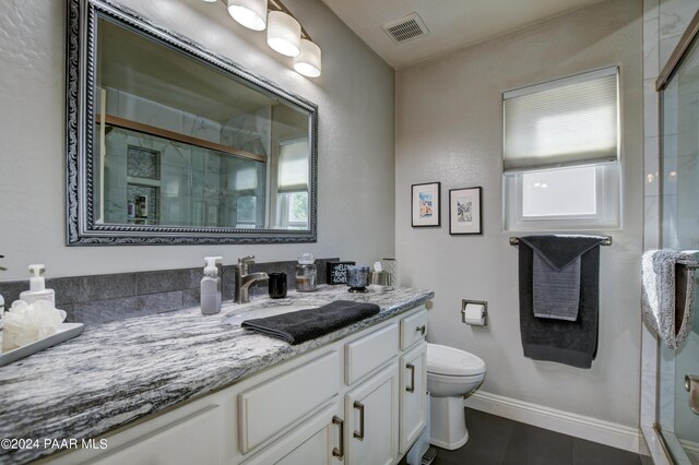 bathroom featuring tile patterned floors, vanity, toilet, and an enclosed shower