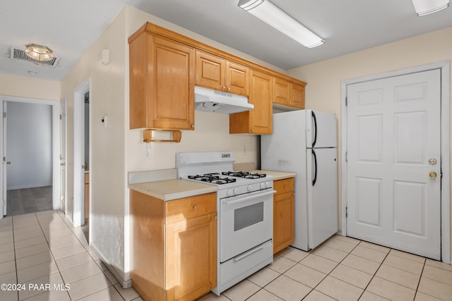 kitchen featuring light brown cabinets, light tile patterned floors, and white appliances