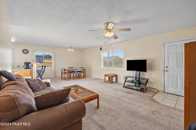 living room featuring ceiling fan, light tile patterned flooring, and a textured ceiling