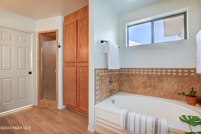 bathroom featuring a shower stall, a bath, and wood finished floors