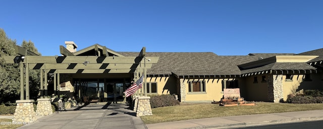 view of front facade with a chimney and stucco siding