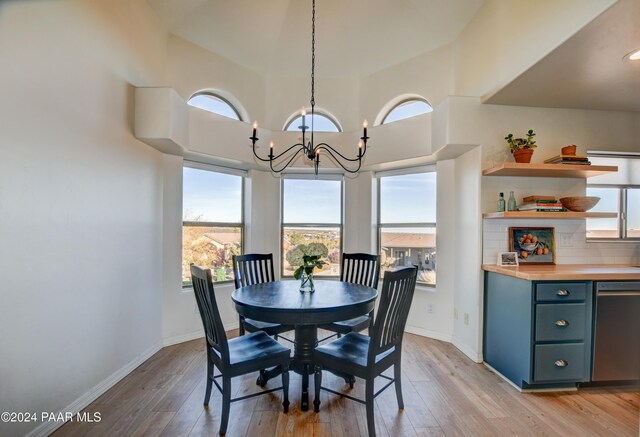 dining room featuring light wood-type flooring, baseboards, and a notable chandelier