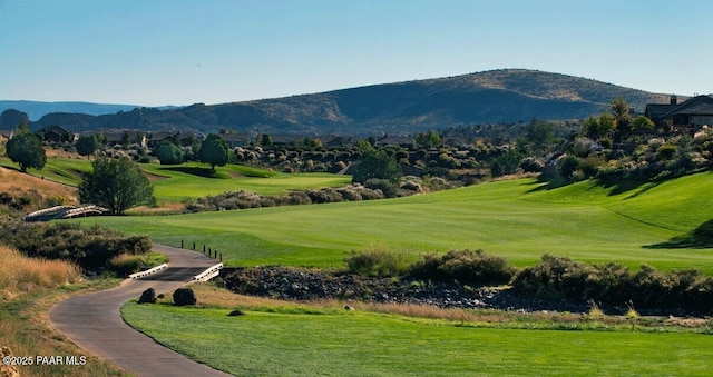 view of home's community with view of golf course, a lawn, and a mountain view