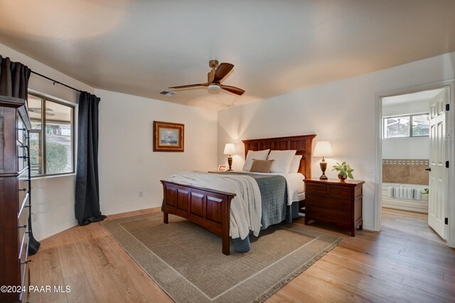 bedroom featuring light wood-type flooring, visible vents, a ceiling fan, radiator, and baseboards