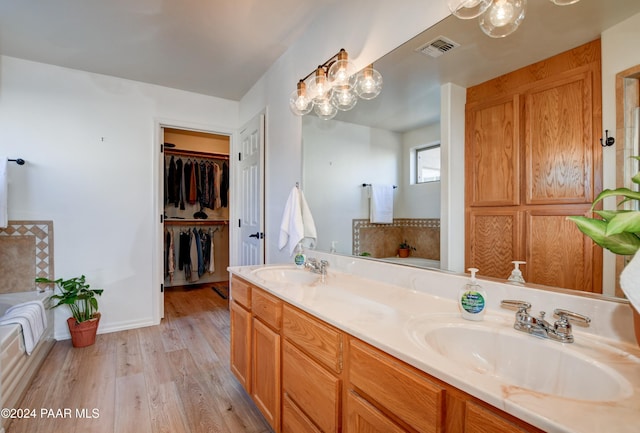 bathroom featuring double vanity, visible vents, wood finished floors, and a sink