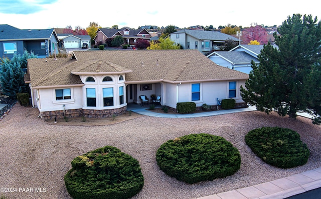 view of front of home featuring a shingled roof, a residential view, and stucco siding