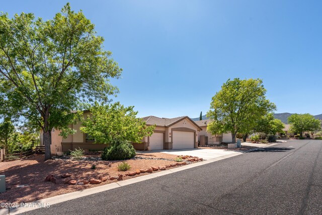 2315 W Desert Willow Dr, Cottonwood, AZ 86326 - view of property hidden behind natural elements featuring concrete driveway, an attached garage, fence, and stucco siding