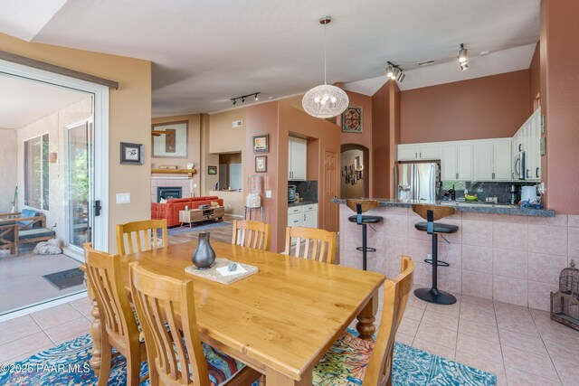 2315 W Desert Willow Dr, Cottonwood, AZ 86326 - dining area featuring arched walkways, track lighting, light tile patterned floors, and a tile fireplace