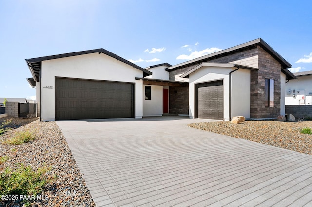 view of front facade with stone siding, stucco siding, a garage, and driveway