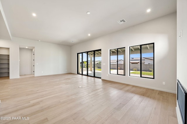 unfurnished living room featuring light wood finished floors, baseboards, visible vents, and recessed lighting