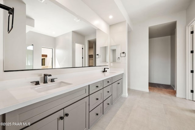 bathroom with a sink, double vanity, baseboards, and recessed lighting