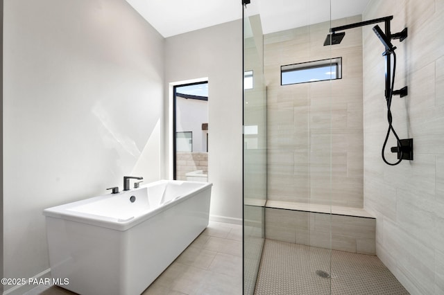 bathroom with a freestanding bath, baseboards, a shower stall, and tile patterned flooring