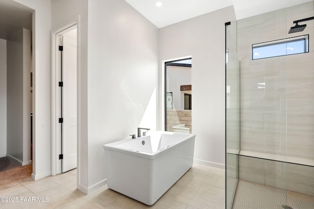 full bathroom featuring a stall shower, a freestanding bath, baseboards, and tile patterned floors