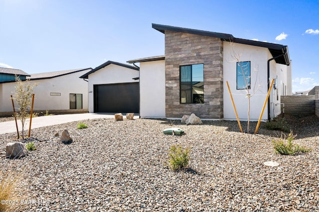 modern home with stone siding, stucco siding, driveway, and a garage