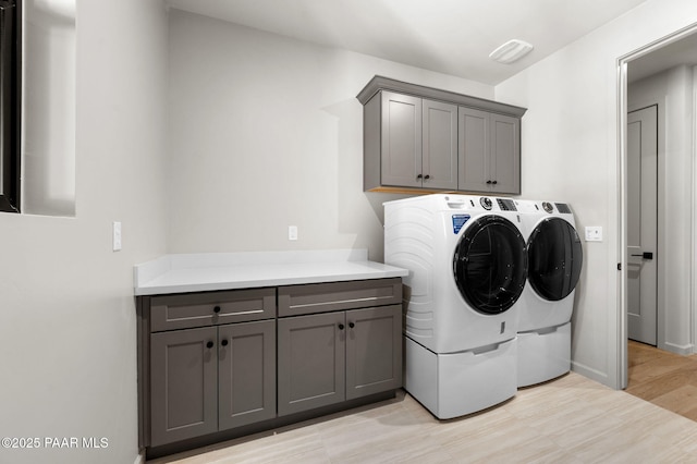 laundry room with separate washer and dryer, cabinet space, light wood-type flooring, and baseboards