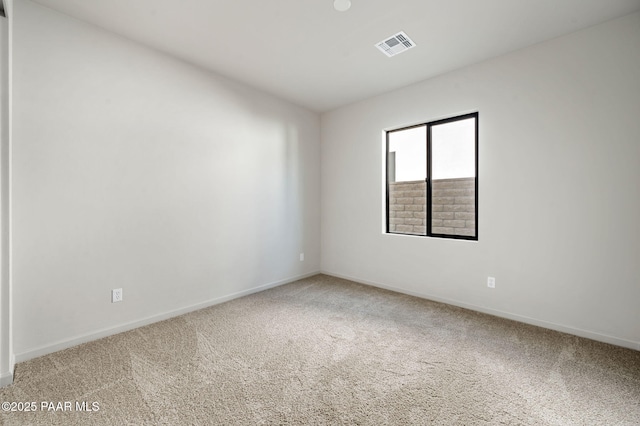 carpeted spare room featuring baseboards and visible vents