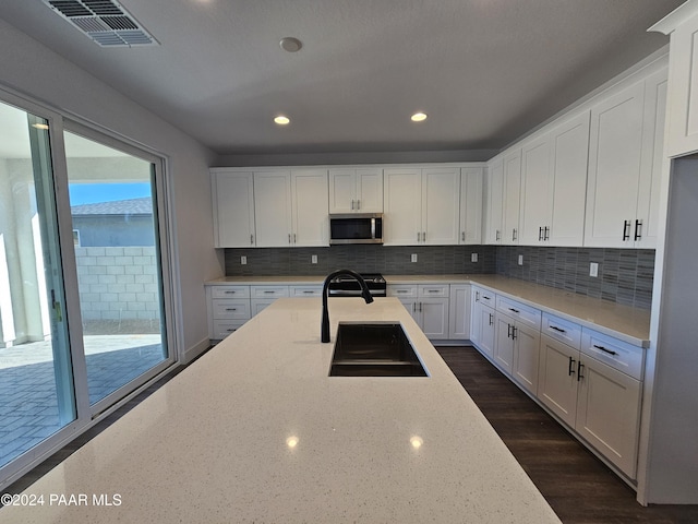 kitchen featuring sink, decorative backsplash, light stone counters, white cabinetry, and stainless steel appliances