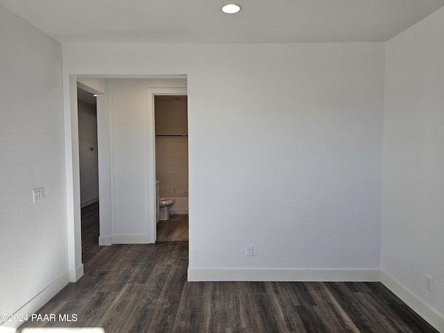 unfurnished bedroom featuring dark hardwood / wood-style floors and ensuite bath