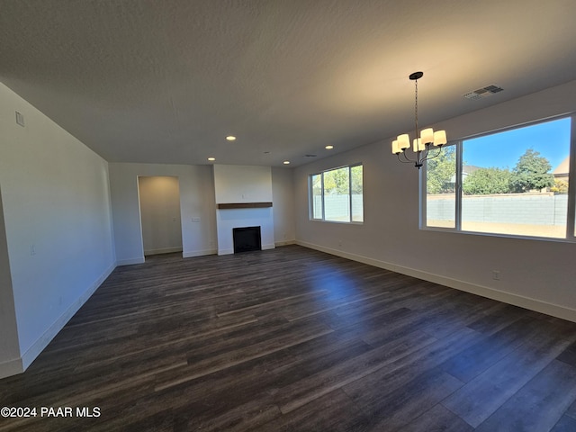 unfurnished living room with a textured ceiling, dark hardwood / wood-style flooring, and a notable chandelier