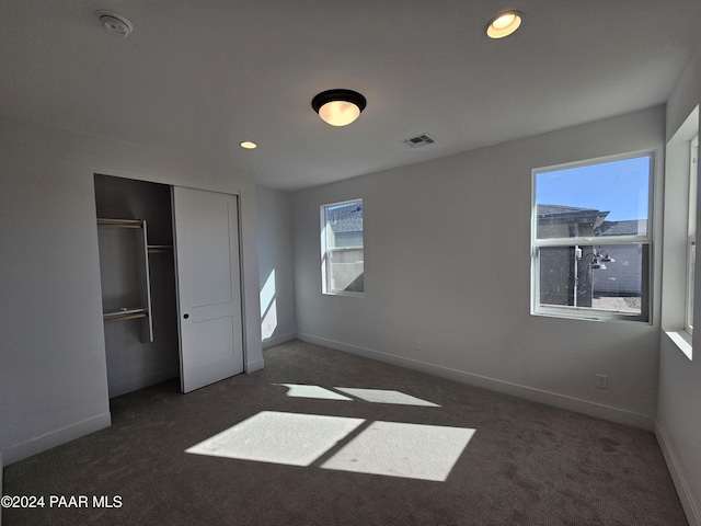 unfurnished bedroom featuring dark colored carpet and a closet