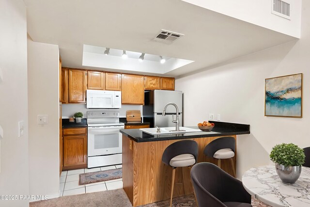 2180 Resort Way Unit S B, Prescott, AZ 86305 - kitchen featuring white appliances, a peninsula, dark countertops, a kitchen breakfast bar, and a tray ceiling