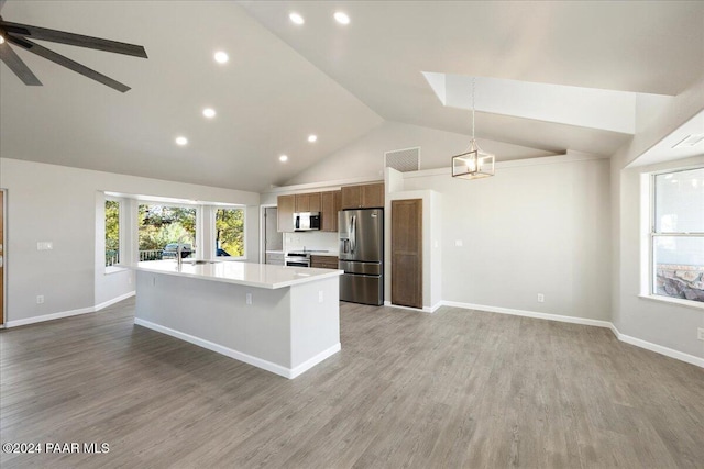 kitchen with pendant lighting, a center island with sink, sink, hardwood / wood-style flooring, and appliances with stainless steel finishes