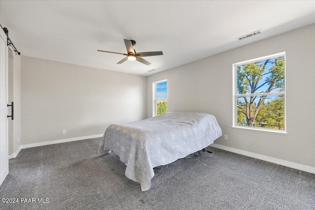 carpeted bedroom featuring a barn door and ceiling fan