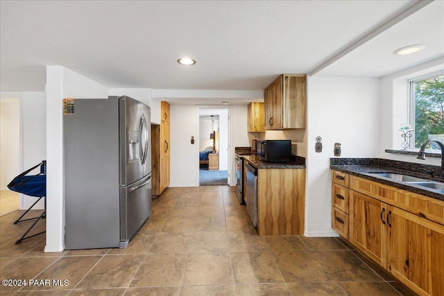 kitchen featuring appliances with stainless steel finishes, dark stone countertops, and sink