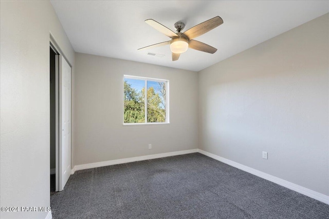 unfurnished bedroom featuring ceiling fan, a closet, and dark carpet