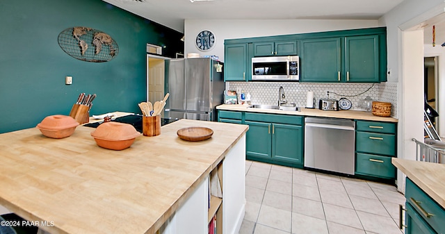 kitchen featuring backsplash, stainless steel appliances, vaulted ceiling, sink, and green cabinets