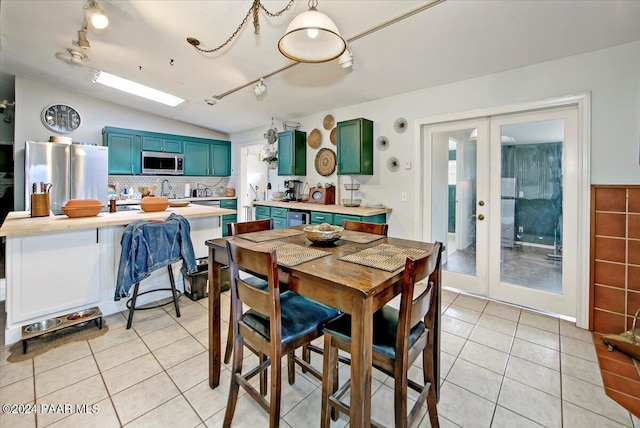 dining room featuring lofted ceiling, light tile patterned floors, track lighting, and french doors