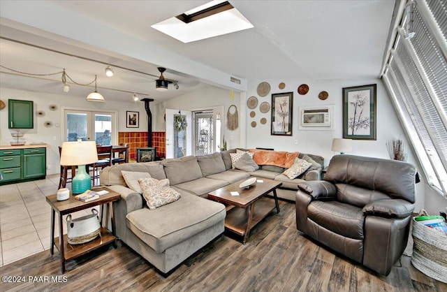 living room with a wood stove, lofted ceiling with skylight, and hardwood / wood-style flooring