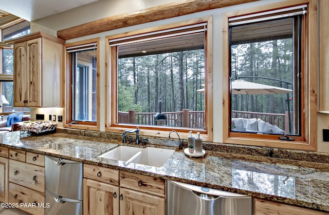 kitchen with light stone countertops, dishwasher, light brown cabinets, and sink